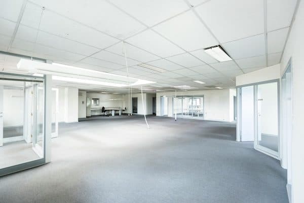 Empty open-plan office floor with grey carpet, suspended ceiling and glass partitions, waiting to be fitted out