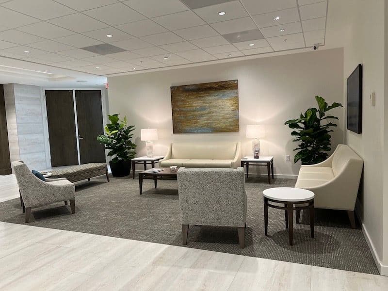 Completed law-firm reception lounge with soft seating, warm lighting, and carpet-tile flooring — Icard Merrill Attorneys & Counselors, an office fit-out by OFDC in Sarasota.