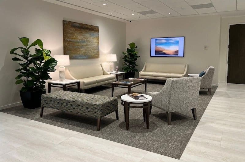 Second lounge view with two cream settees, patterned wing chairs and round side tables