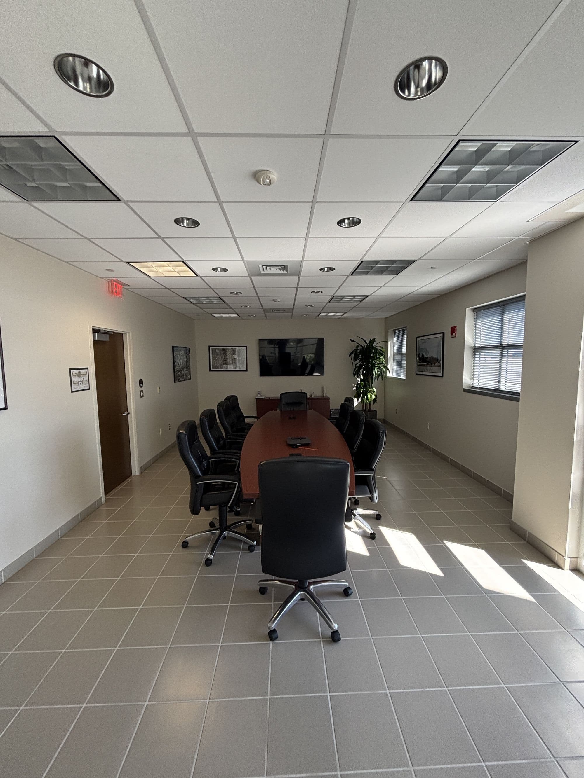 Airport administration conference room with a long table, black executive chairs and a wall display