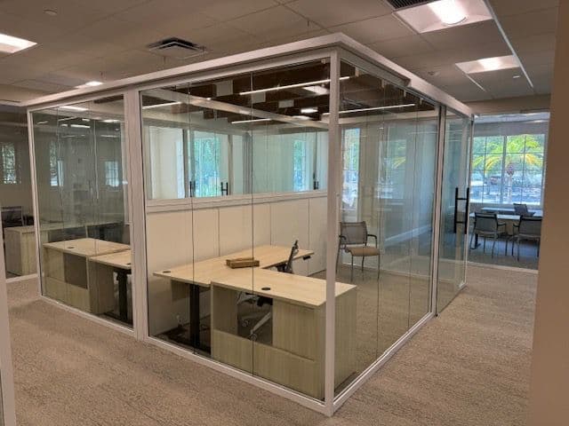 Glass-walled offices with height-adjustable sit-stand desks and natural light — Sarasota Community Foundation, furnished by OFDC in Sarasota.