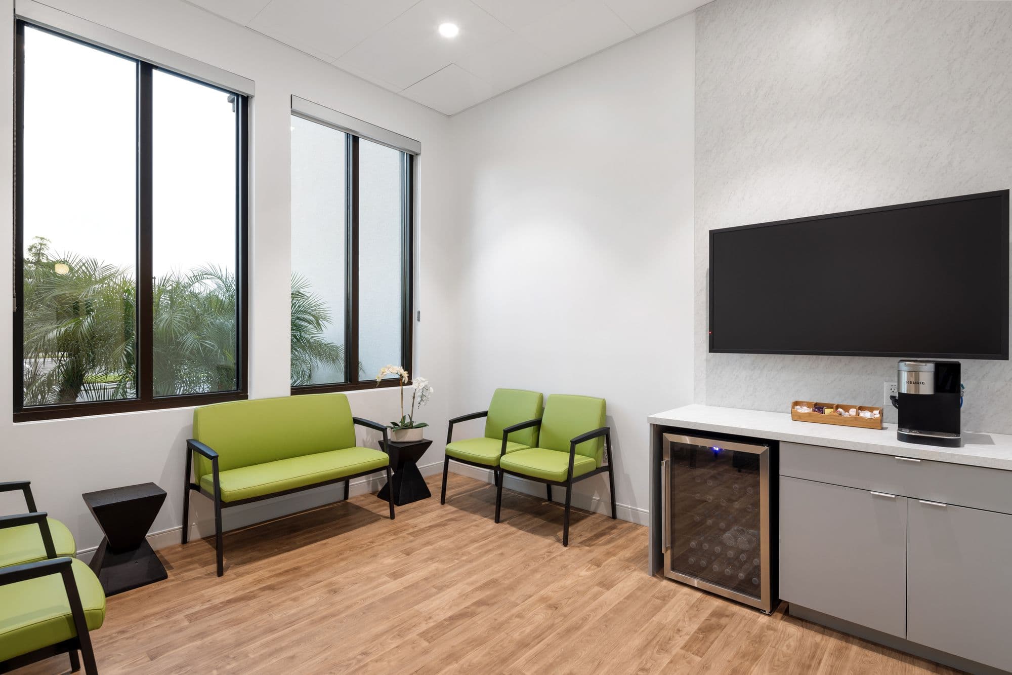 Patient waiting area at Wasserman Ulitsky Dermatology in Venice with healthcare-grade seating, resilient flooring, and palms outside the windows