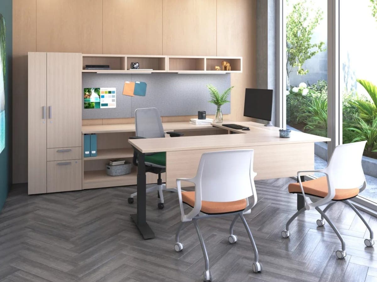 Light wood AMQ Activ Pro desk on a sit-stand base with a storage tower and guest chairs