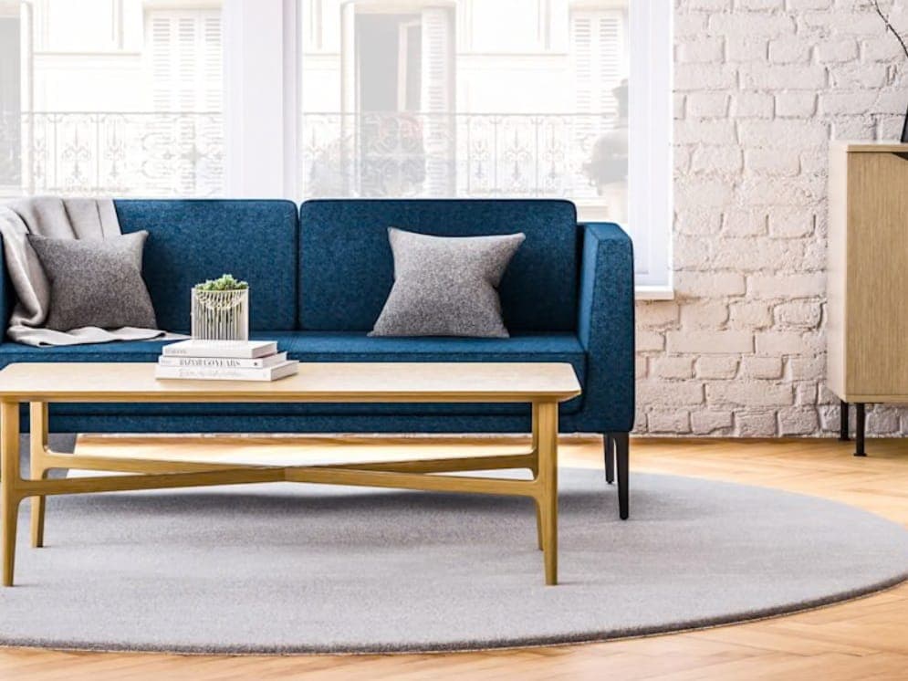 Blue JSI Arwyn sofa with a light wood coffee table on a round rug